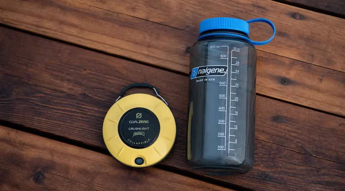 Etekcity lantern collapsed flat next to a water bottle for scale, showing how small it packs