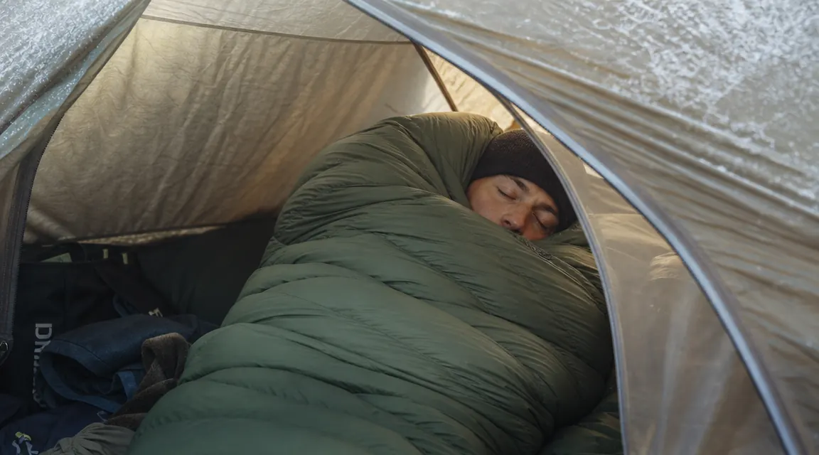 Camper sleeping on the Artemis pad inside a tent on a frosted autumn morning, sleeping bag pulled up to shoulders
