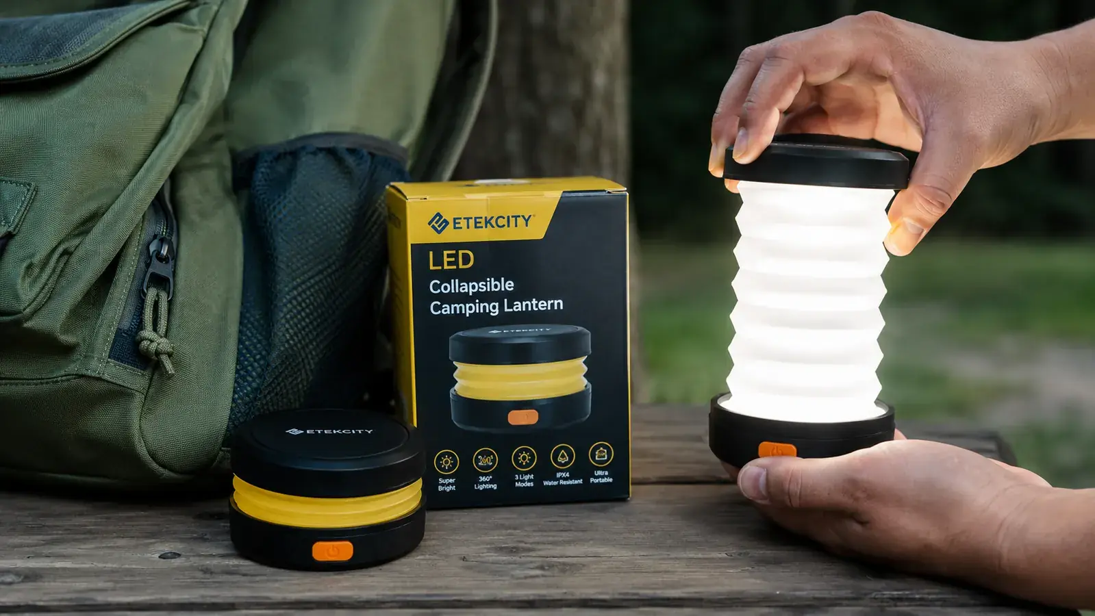 Etekcity LED lantern collapsed flat next to a camping pack, showing its compact size before being pulled open